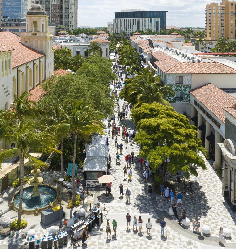 Aerial view of a busy downtown pedestrian street lined with palms and shops